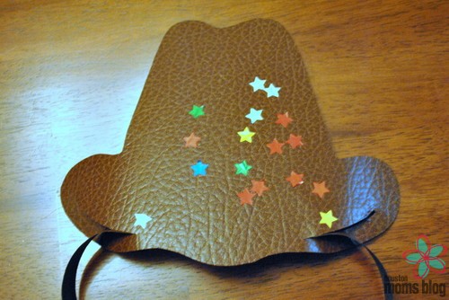 The cowboy hat cutout decorated with stars and the strips inserted through slits at the rim of the cowboy hat. Logo: Houston moms blog. 