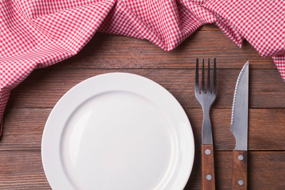 Empty plate on tablecloth on wooden table