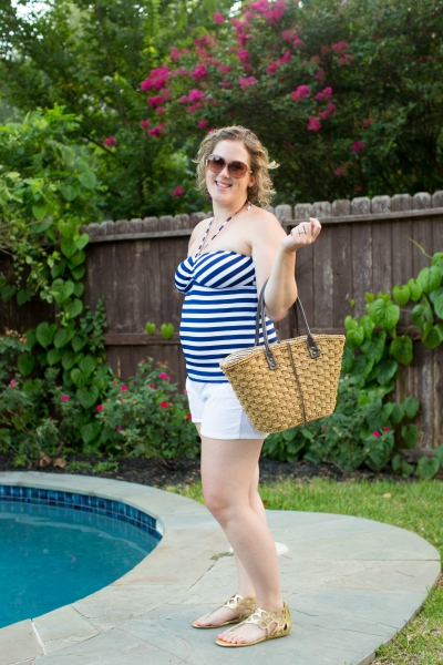 A smiling woman in a tankini standing next to a pool. 