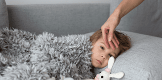 mother's hand on sick child's forehead