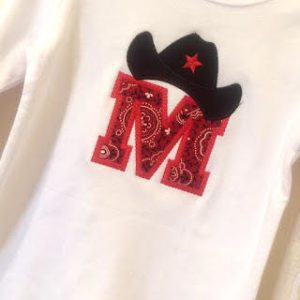 A child's t-shirt with an embroidered M and a cowboy hat. 