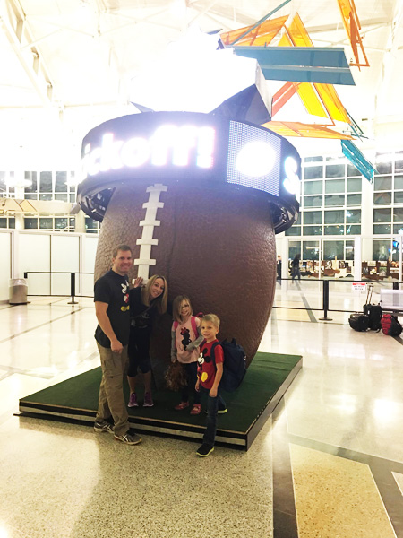 A family of four in front of a large football. 