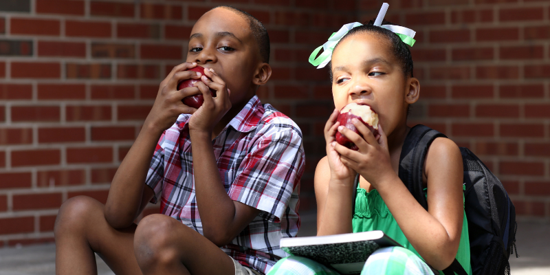 children sit on step eating apples