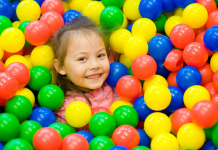 A smiling young child in a toy ball pit.