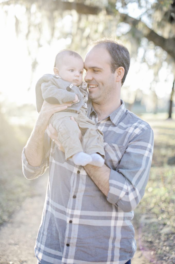 A smiling man holding a baby. 