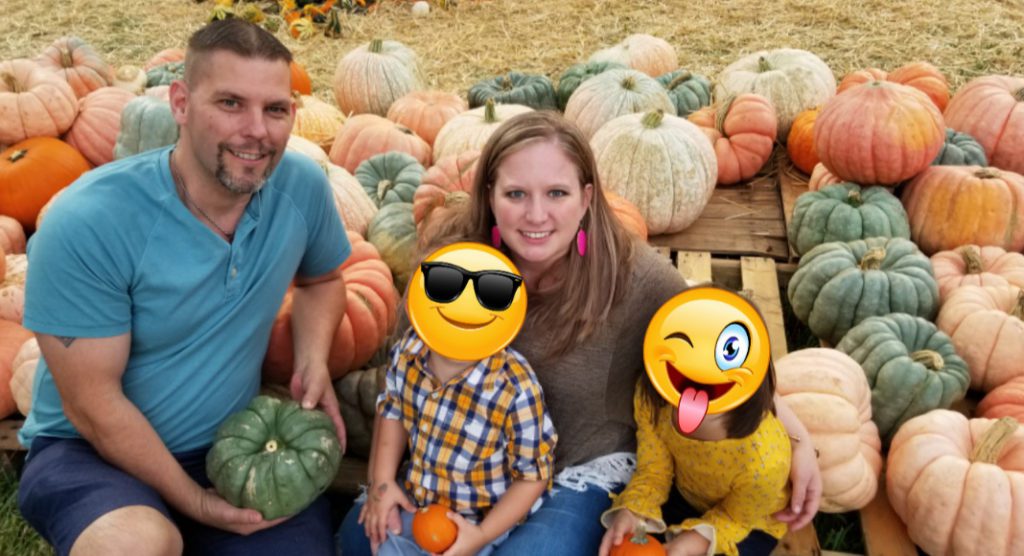 family in pumpkin patch with foster children's faces covered with emoji masks