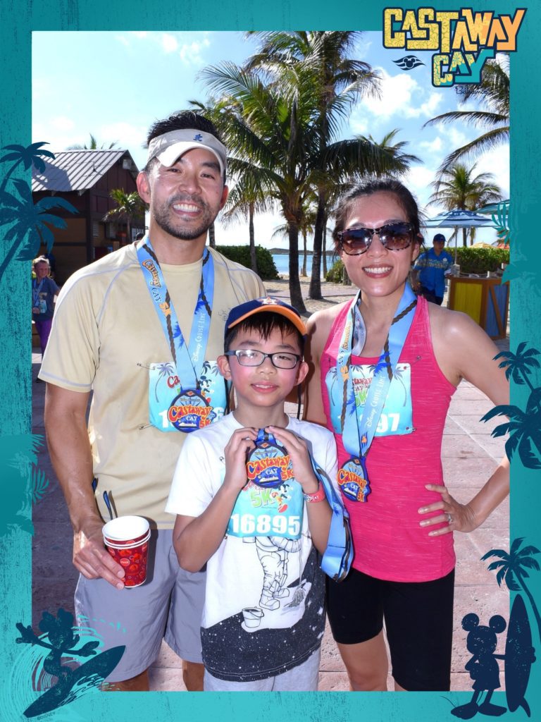 A photograph in a Castaway Cay frame of a mother, father and son all wearing Castaway Cay 5 K medals.