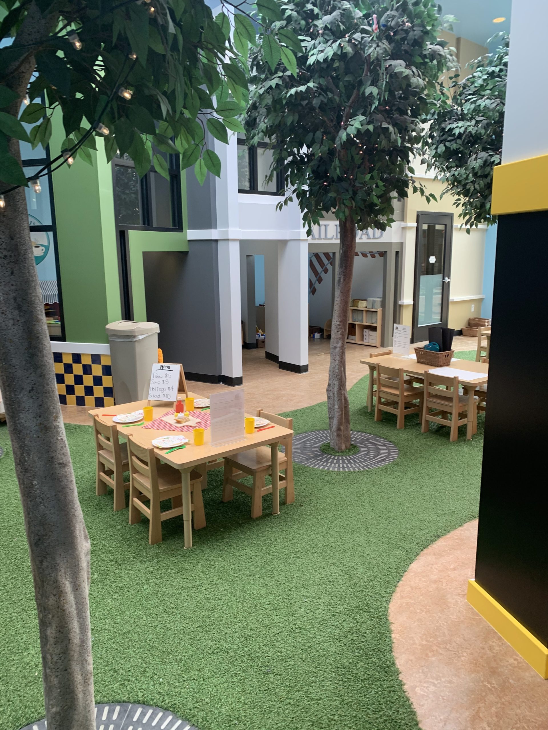 A child's eating area with fake grass and trees. 