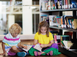 Two children sitting on a library floor and reading.