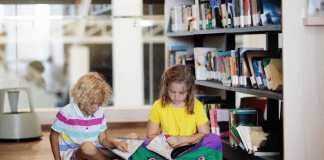 Two children sitting on a library floor and reading.
