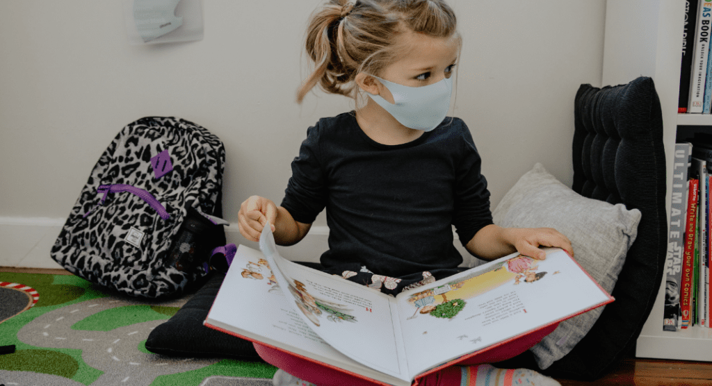 girl with mask reading a book for National Family Literacy Month