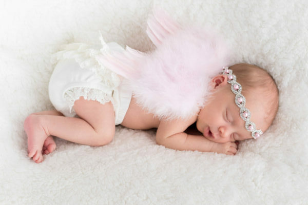 newborn baby sleeping wearing pink angel wings