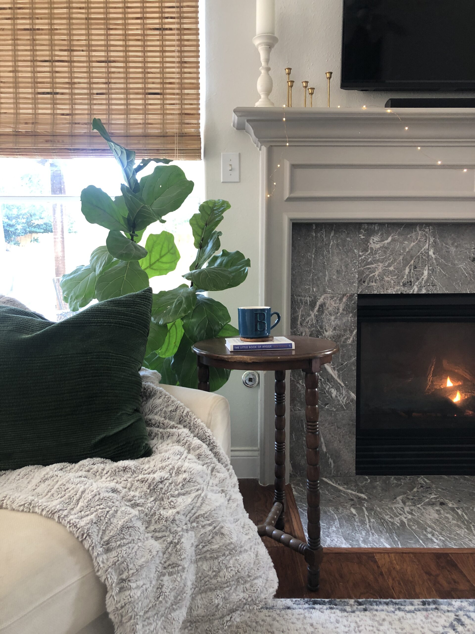 cozy hygge living room with fireplace, soft blanket, and cup of tea