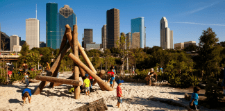 A photograph of a wooden playground with Houston in the background.