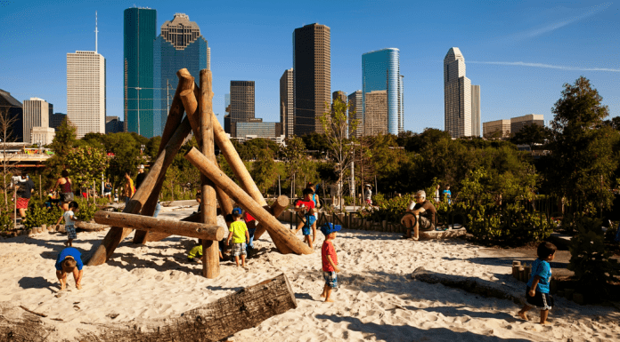 A photograph of a wooden playground with Houston in the background.