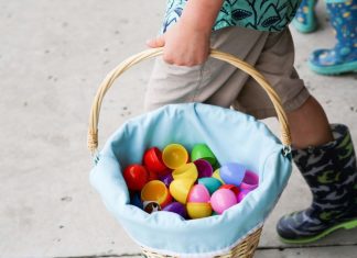 A child carrying a basket filled with open plastic eggs.