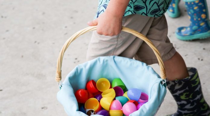 A child carrying a basket filled with open plastic eggs.