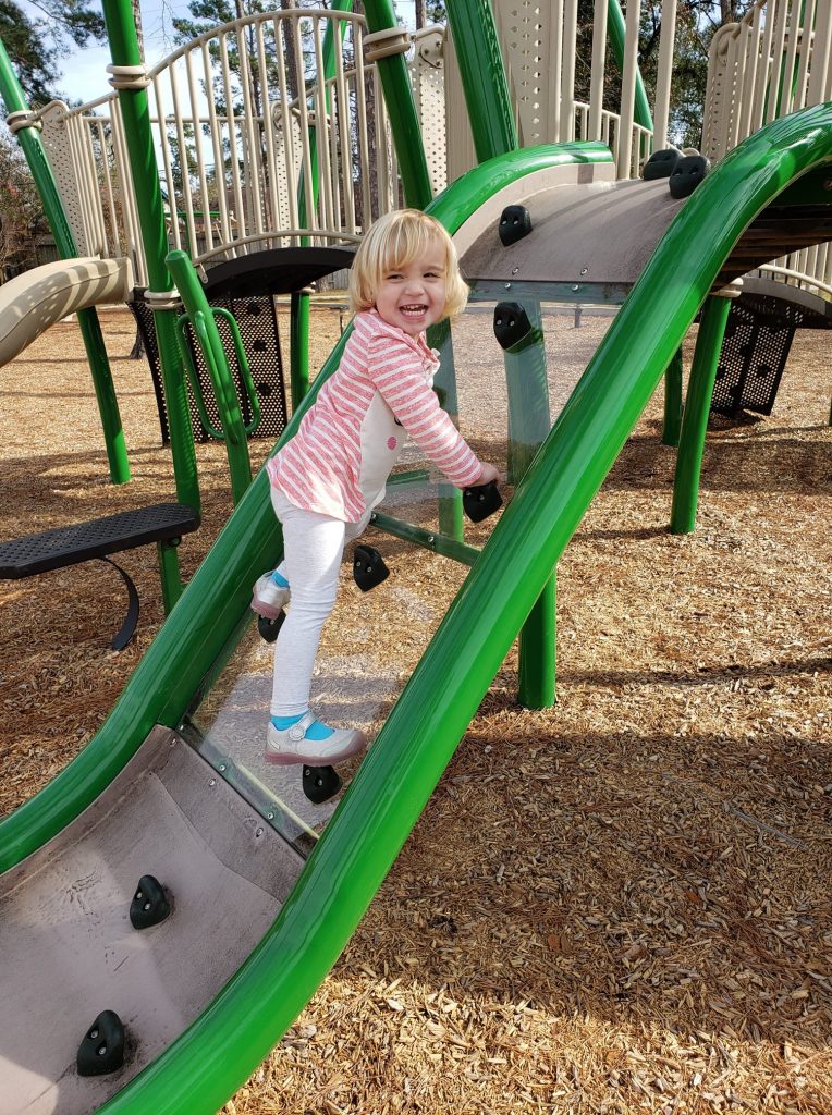 A young child climbing a ramp at a playground. 