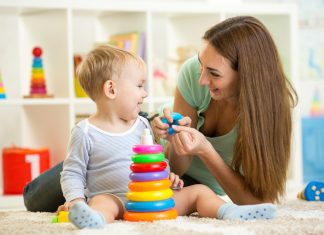 A mother playing with a toddler with a stacked ring toy.