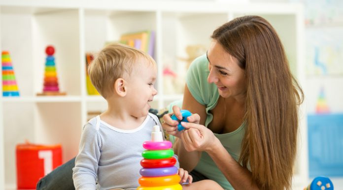 At-Home Activities for Little Ones to Keep Summer Learning Alive A mother playing with a toddler with a stacked ring toy.