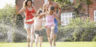 Surviving Summer When You’re a Bad Summer Mom A family of four running through a sprinkler.