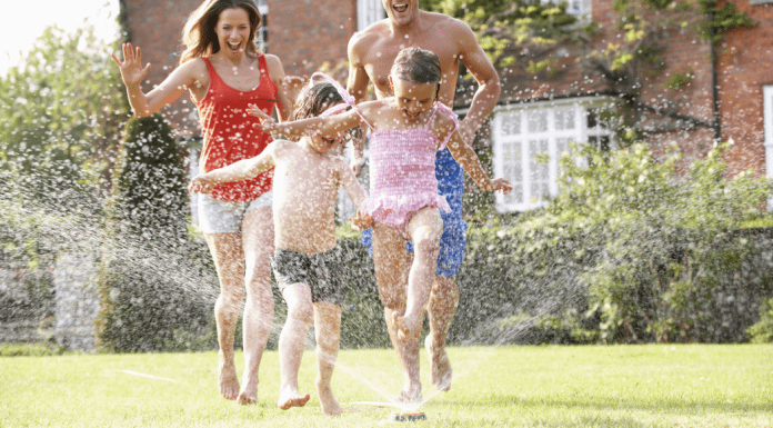 Surviving Summer When You’re a Bad Summer Mom A family of four running through a sprinkler.