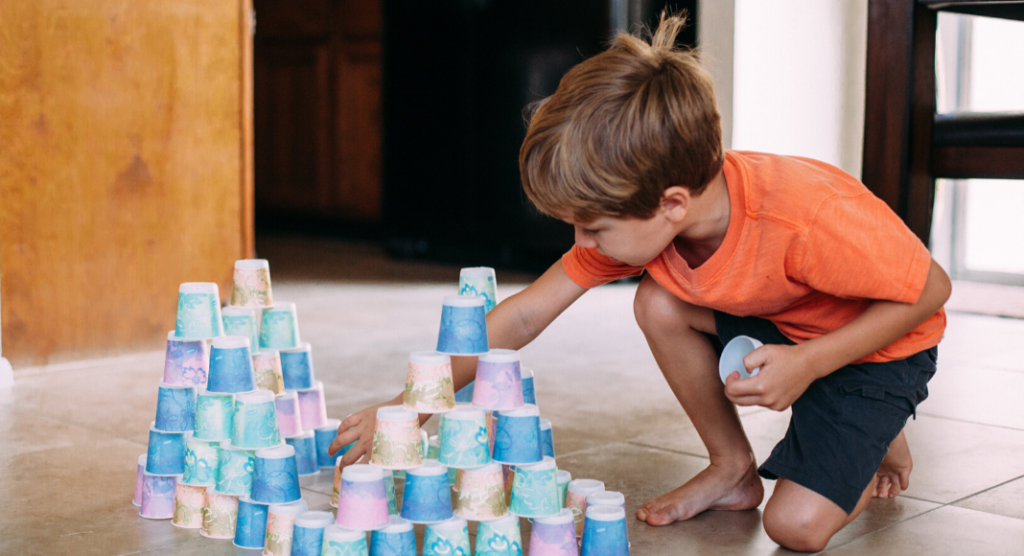 preschooler kneeling while stacking cups