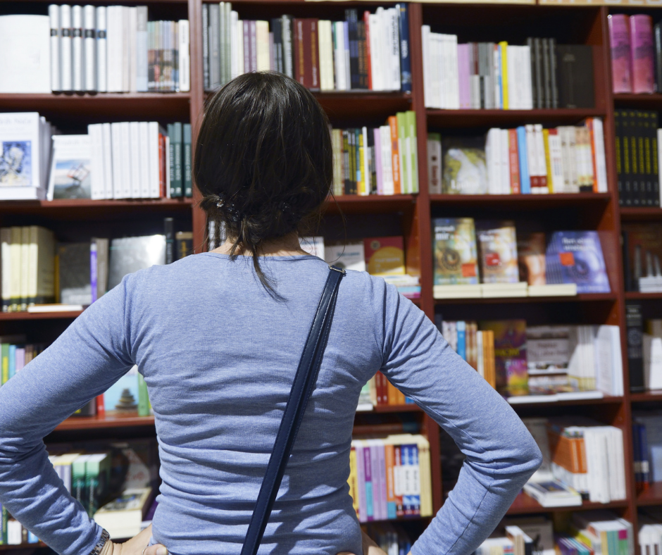 A woman facing away from the camera looking at shelves of books. 