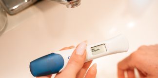 Another Baby at 38: Sorting Through my Big Feelings A woman holding a pregnancy test displaying the text Not Pregnant.