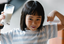 small girl holding glass of milk