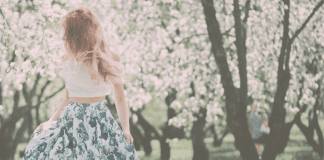A woman in a grove of flowering trees.