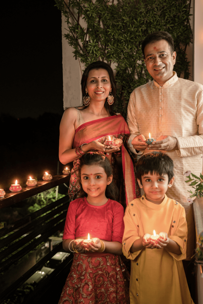 family of four celebrating Diwali holding lit candles