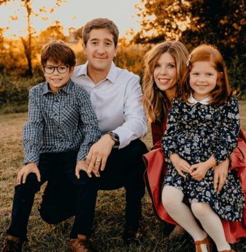 A photograph of a family of four pose for a family photo.