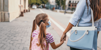 working mom holding daughters hand as they walk to school