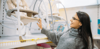 A woman pushing a baby swing on a store shelf