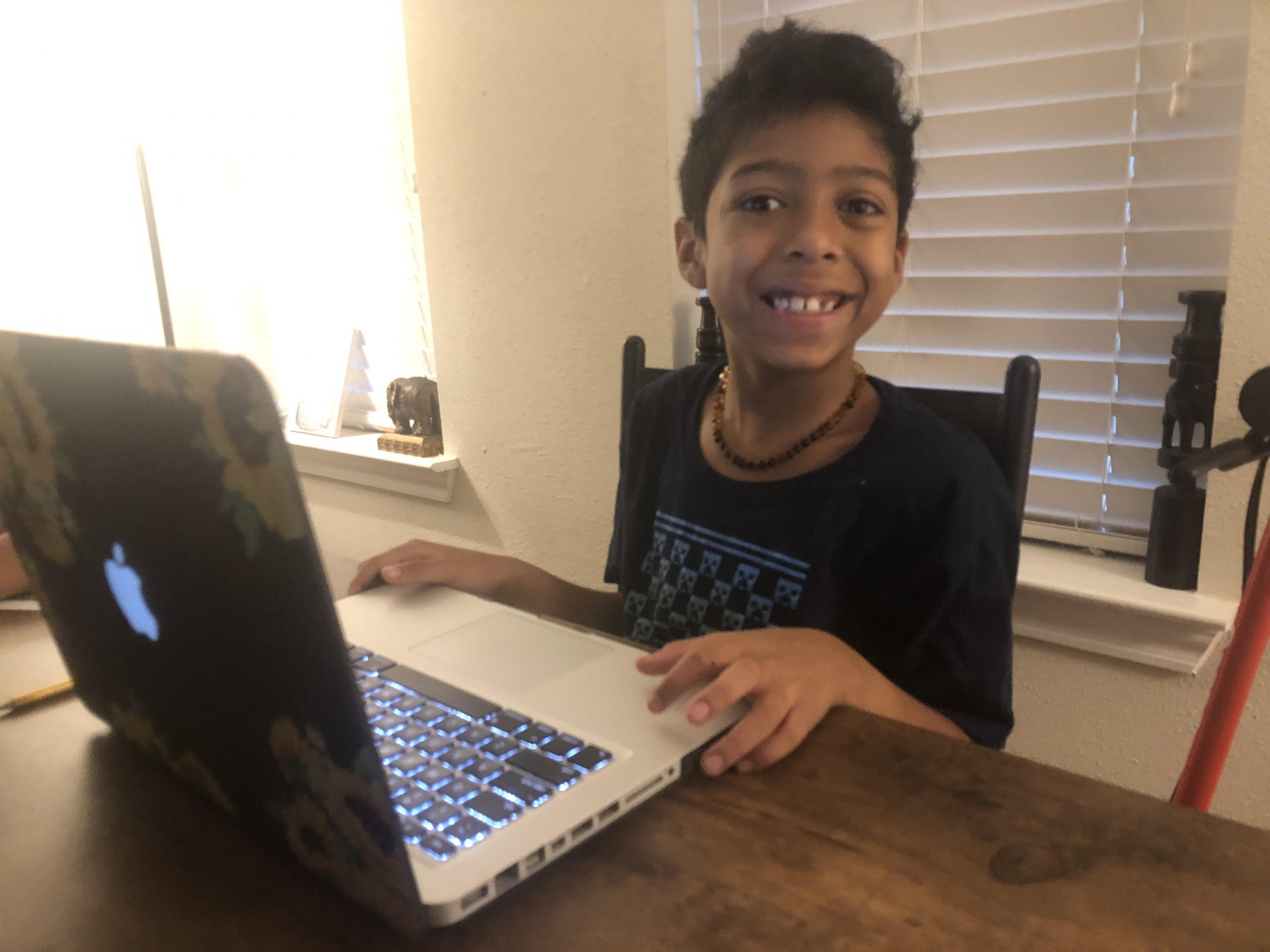 Young boy smiling while he works on laptop