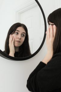 woman gazes at herself in a mirror