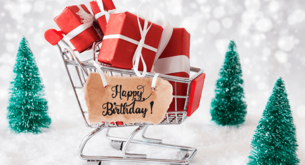 cart of presents with Happy Birthday sign with Christmas trees in the background