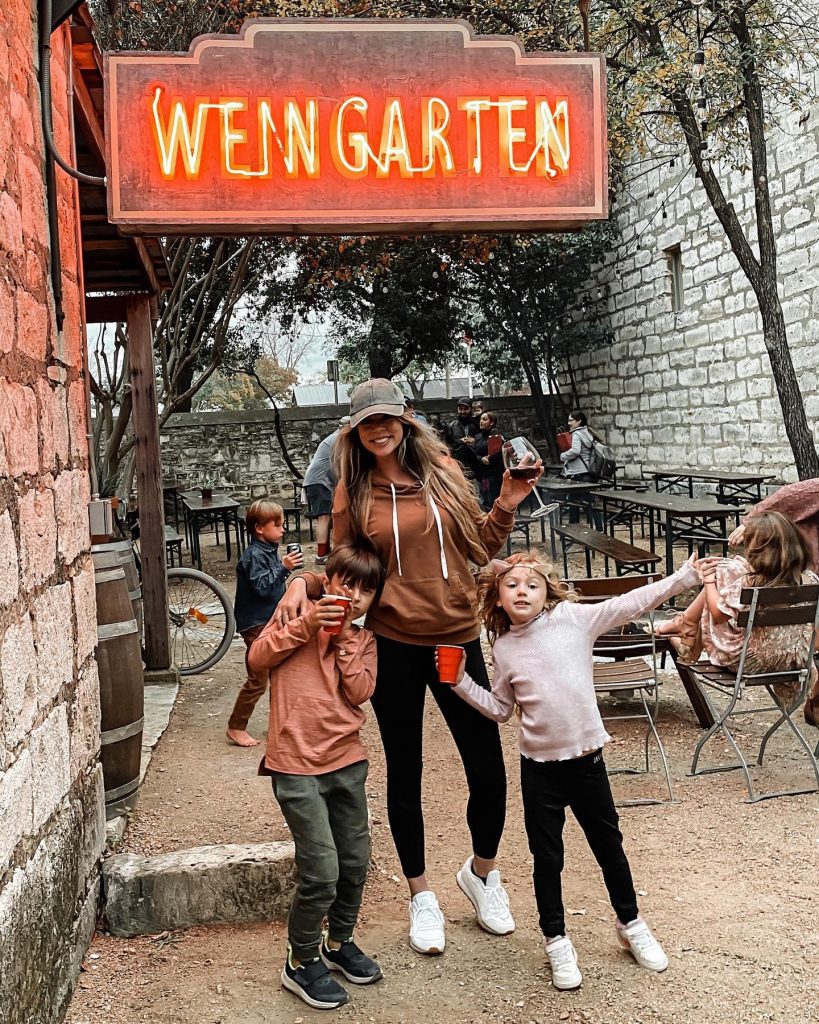 mother and two kids hold drinks under sign that says Weingarten