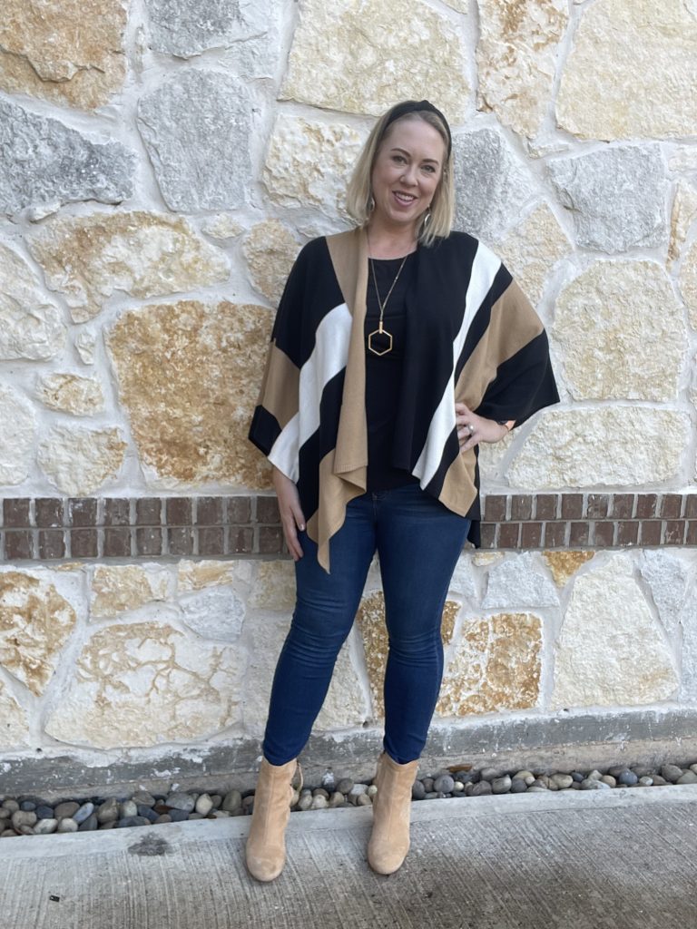 woman winterizes her warm weather wardrobe with jeans and a lightweight cape sweater