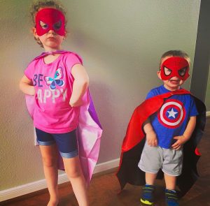 preschooler and toddler in superhero capes and masks