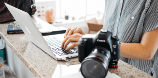 Momtographer Resolutions Part 2: Organizing and Storing Family Photos woman typing on computer with camera on desk next to her