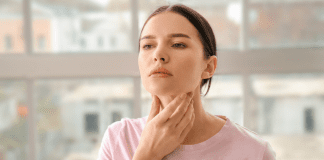woman touching her neck where her thyroid is located