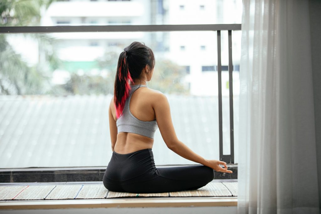 woman in yoga clothes sits in a meditative pose