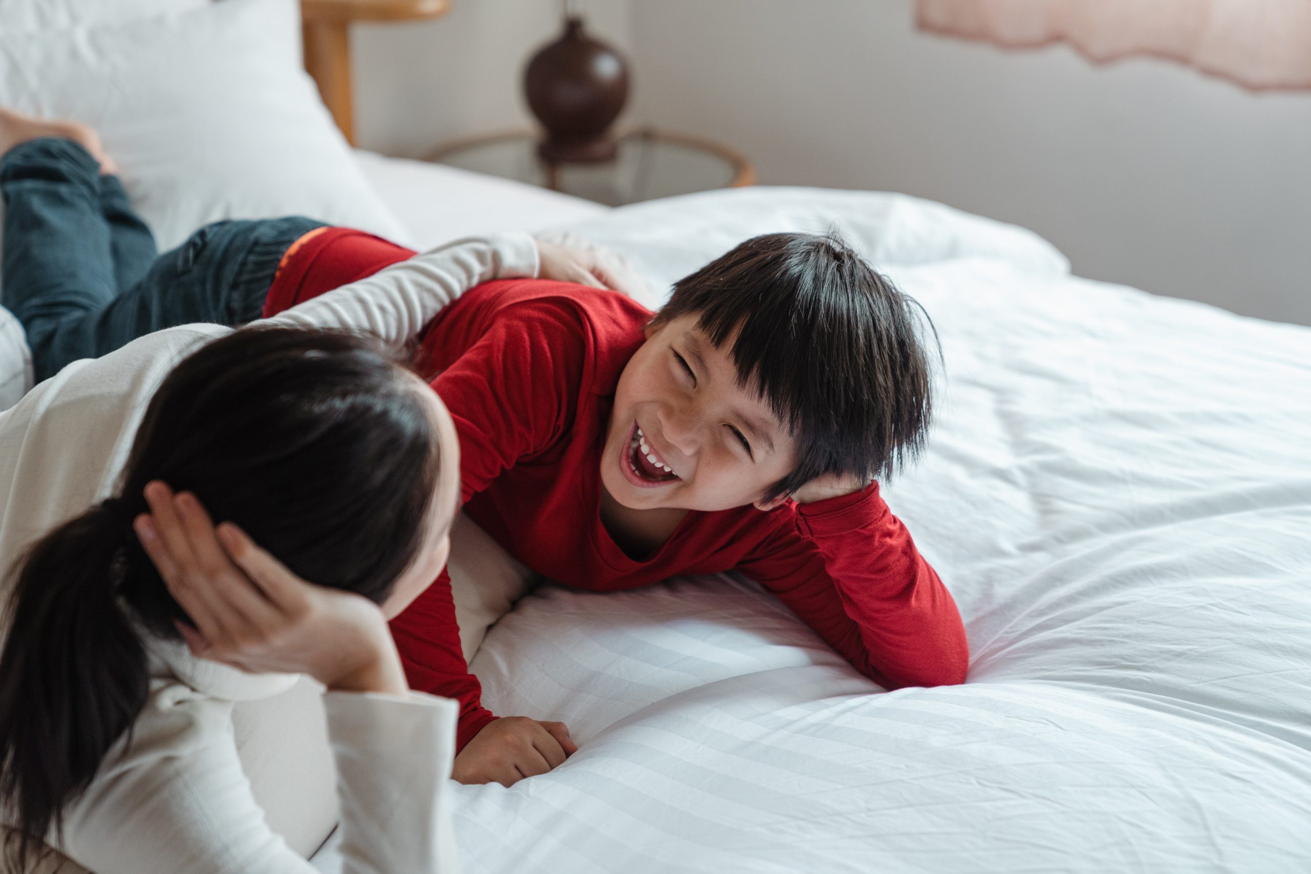 mother and son lay on bed laughing