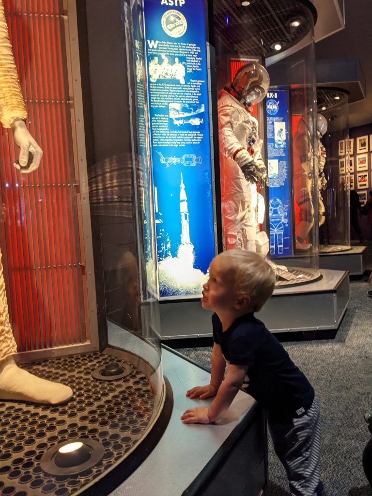 toddler stares up at astronaut manequin