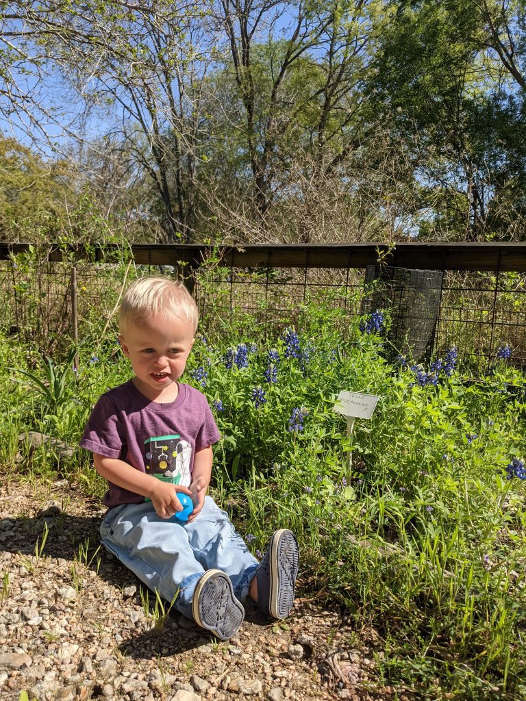 toddler sits in grass on walking trail