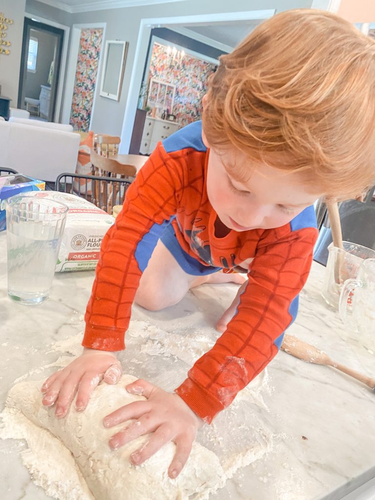toddler on counter kneading bread
