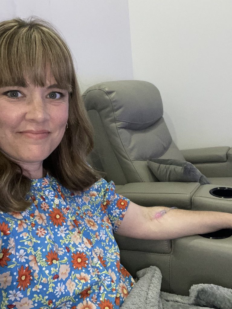 woman sits in chair receiving IV therapy