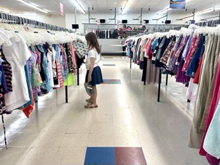 woman looking at clothing in a thrift store